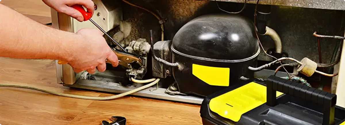 Refrigerator repair technician fixing the compressor and wiring in Temple City, CA