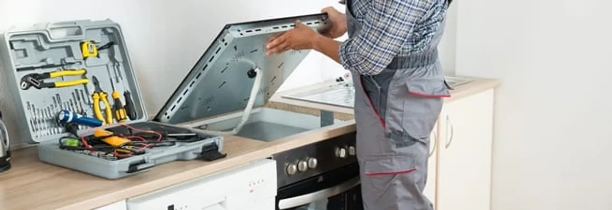 Cooktop repair technician lifting a built-in stovetop for service in Pasadena, CA
