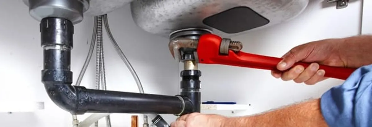 Garbage disposal repair technician tightening the sink drain and disposal connection in Pasadena, CA