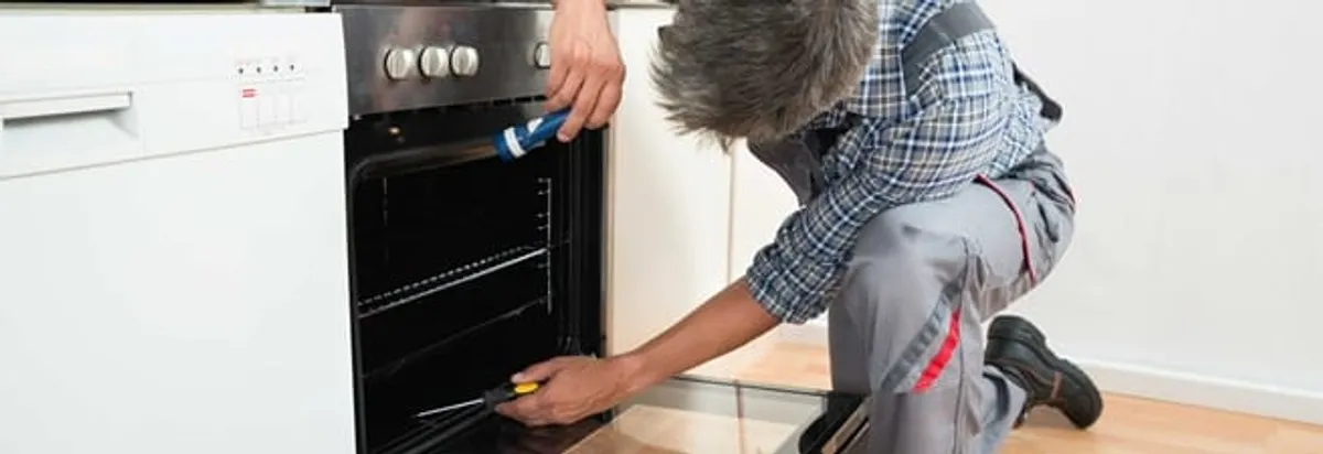 Oven repair technician inspecting and servicing an electric oven in Pasadena, CA