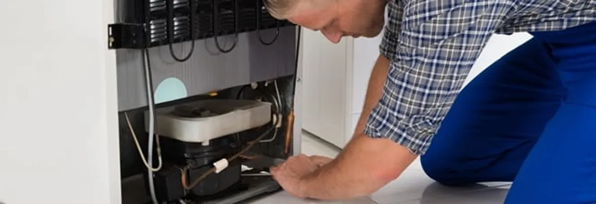 Refrigerator repair technician servicing the compressor and condenser area in Pasadena, CA