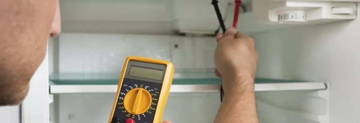 Refrigerator repair technician testing electrical components with a multimeter in Pasadena, CA